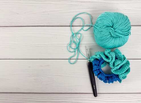 Yarn ball, crochet hook and ruffled scrunchie with copy space