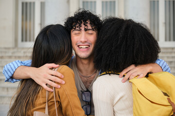 Obraz premium Smiling young man embracing two female friends, showing a moment of joy and reunion