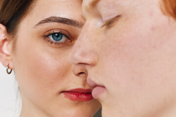 Obraz premium Portrait of two young women with different skin tones close together, showing facial features, eye detail, natural expression and minimal makeup in studio lighting.