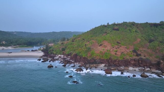 Lush green mountains overlooking Goa coastline, tropical beach , serene sea waves, aerial view of western India, scenic tropical landscape, tranquil environment, peaceful nature, sunrise or sunset lig