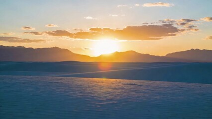 Obraz premium Golden sunset over vast white sand dunes with distant mountain silhouettes