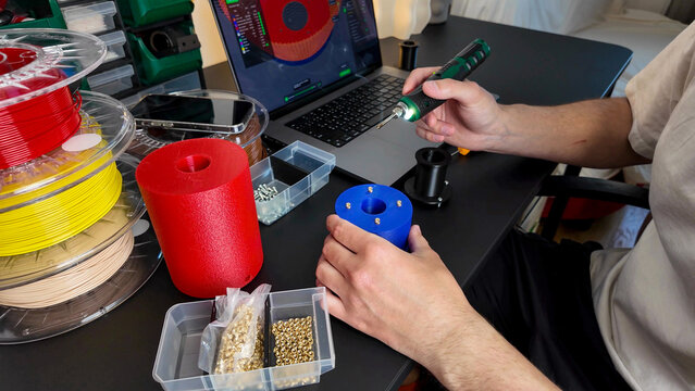 Crafty hands of a Caucasian male assembling vibrant 3D printer parts celebrate Inventors' Day with mechanical alchemy, innovation festivity