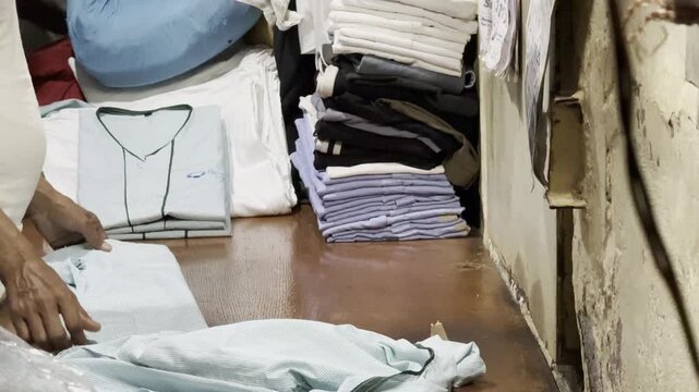 Mumbai, India &ndash; January 25, 2026: Laundry worker folding clean clothes inside the Dhobi Ghat open-air laundry complex, a historic washing district in Mumbai.