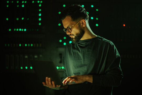 Developer working on laptop in server room