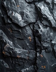 A detailed close-up texture of jagged, dark gray volcanic rock with subtle orange mineral deposits.