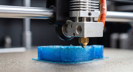 3D printer nozzle tip extruding blue plastic filament close up