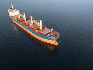 Fototapeta premium High angle aerial drone shot of an empty bulk carrier ship floating in the deep blue Baltic Sea water during winter