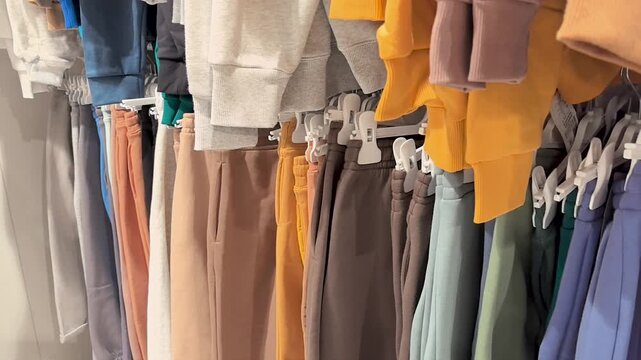 Brightly colored athletic pants hang neatly on racks in a local store. Shoppers browse through a variety of styles and shades, admiring the trendy selections available.