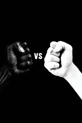 Fototapeta premium Two fists in black and white face each other, showing a clear choice and representing strong contrasts in ideas and perspectives.