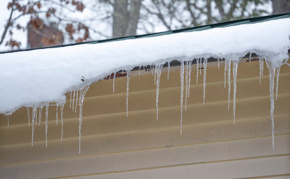 snow sliding and falling from the roof with icicle