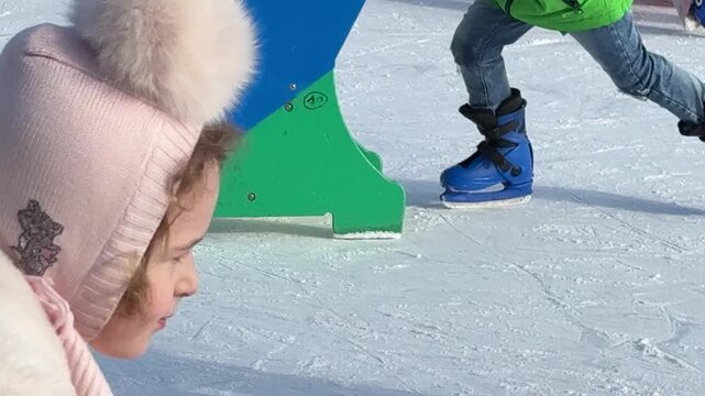 Close up of ice skates and legs on outdoor skating rink, model released for the only recognizable person