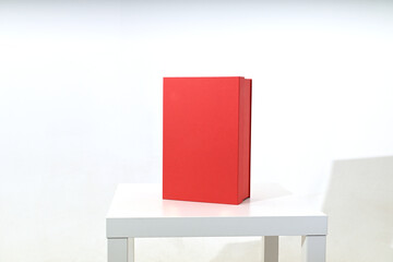 Bright red designer gift box on a white background in the studio on the table