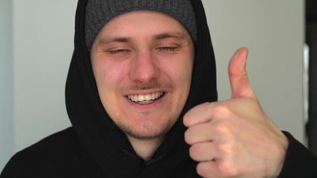 A man in a hoodie makes a thumbs-up gesture.
A gesture of approval and positivity.
Very good, super, delighted.
