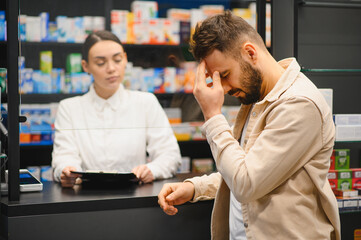 Man suffering headache consulting pharmacist at drugstore