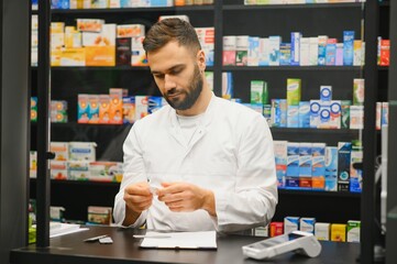 Male pharmacist working at pharmacy counter preparing medication