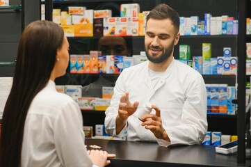 Pharmacist advising female customer on medicine at pharmacy