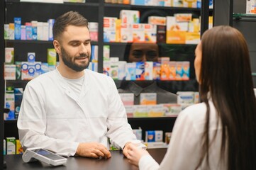 Pharmacist assisting customer paying for medication in drugstore