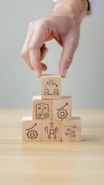 Change management process concept with hand arranging wooden blocks showing strategy, growth, learning, leadership, and teamwork icons, symbolizing organizational transformation, business improvement