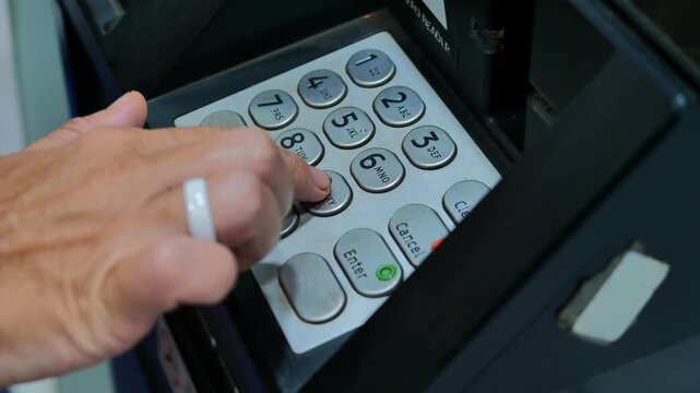 Close up of adult hand pressing keypad buttons on automated teller machine, entering pin code during cash withdrawal, focused banking action, secure financial transaction moment, everyday money manage