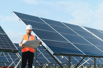 Engineer reviewing blueprint at solar panel field