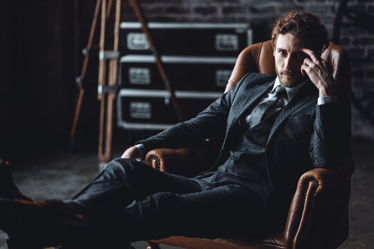 Portrait of a handsome young stylish sexy man in a white shirt, , suit, jacket posing in studio with a loft interior. Black and white. Casual clothes, modern style. Male groom wedding photoshoot