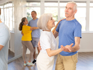 Obraz premium Group of elderly pensioners learn to dance a couple tango dance in a dance class