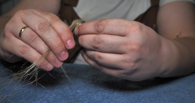 Professional plumber's hands carefully wrapping natural oakum fiber around a pipe fitting thread to create a watertight seal for plumbing installation, repair, or maintenance.