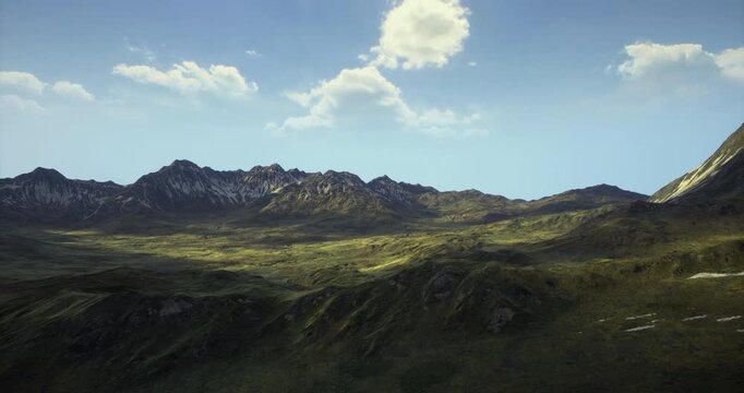 Lush green valleys stretch through rugged mountain terrain under a clear blue sky. Sunlight casts soft shadows, enhancing the natural beauty of this serene landscape.