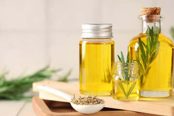 Rosemary with bottles of essential oil on white tile background