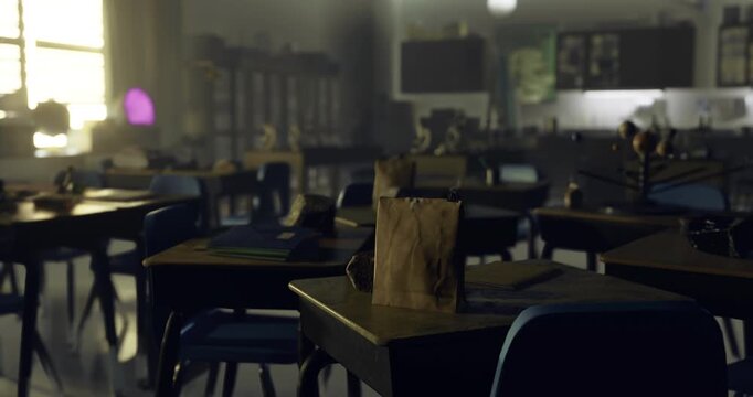 Sunlight streams through windows, illuminating the empty classroom filled with desks and chairs. A brown paper bag sits on one desk, indicating signs of a recent presence.