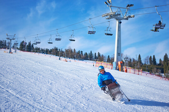 A man in a blue jacket confidently skis down a mountain