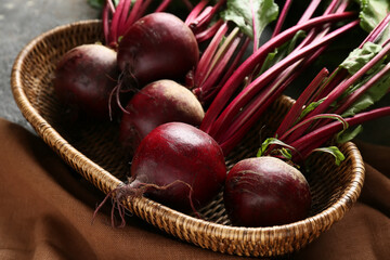 Wicker basket with fresh beetroots on grey grunge background
