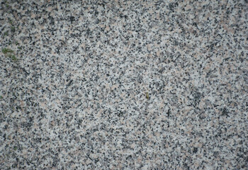 Obraz premium Close-up of a natural marble or granite stone surface with fine speckled texture and neutral gray tones. The detailed rock pattern highlights the durability and organic structure of polished granite.