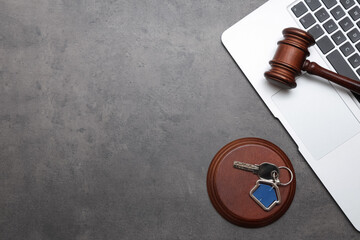Laptop with auction gavel and key from house on dark background