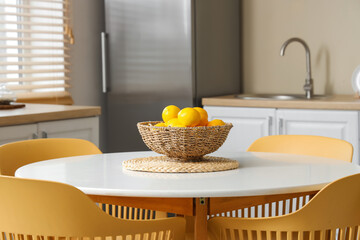 Fototapeta na wymiar Wicker bowl with lemons on dining table in kitchen