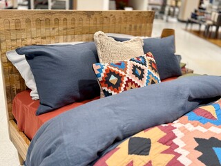 Stylish bedroom interior with colorful patterned bedding, decorative pillows, and woven headboard, cozy modern home decor setup with warm textures and inviting atmosphere.