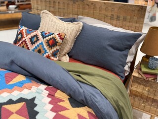 Stylish bedroom interior with colorful patterned bedding, decorative pillows, and woven headboard, cozy modern home decor setup with warm textures and inviting atmosphere.