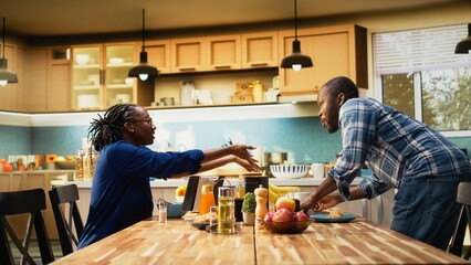 Obraz premium Black woman eating alone after her boyfriend is rushing to leave for work, running late and skipping breakfast. Morning routine in a hurry for man being late for his office job, lifestyle.