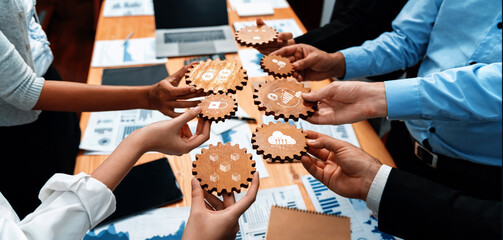 A dynamic business meeting showcasing hands of diverse professionals collaboratively holding wooden gears, symbolizing teamwork and innovative planning in a corporate environment. Amity