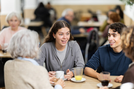 Multi-age group of people in restaurant. Organization of meetings, coffee breaks, and festive dinners, family gatherings. Relatives chatting, joking, speaking, have nice conversation, enjoy meeting