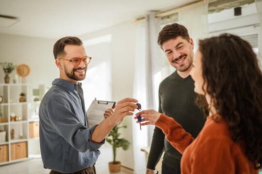 Realtor giving new home keys to smiling couple