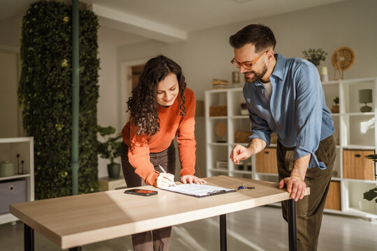 Real estate agent giving pen to woman for signing agreement