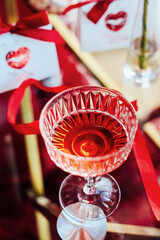 Red drink in a crystal glass with decorations on a table at a Valentines day party event