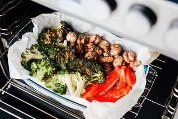 Fresh broccoli mushrooms and red peppers roasting in an oven for a healthy meal