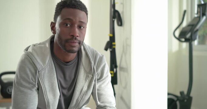 Mid adult African American man checking smartwatch and smiling before sharing workout at home gym