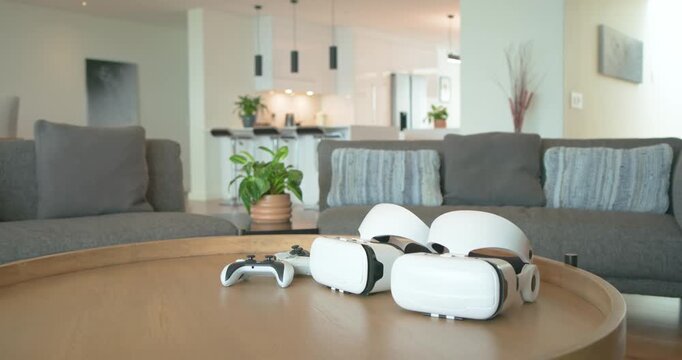Camera pushing in, panning right, highlighting VR headsets and controller on table in living room
