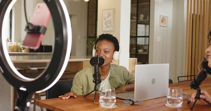 Greeting co-host in studio, woman speaking into mic shifting to ringlight phone camera wrapping up