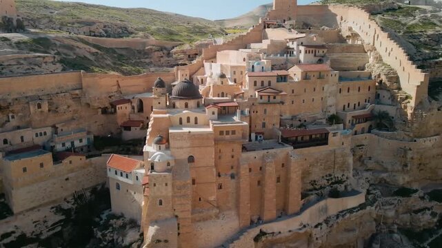 Aerial Cinematic View of Mar Saba Monastery in the Judean Desert, an Ancient Christian Landmark Built into Rock Cliffs.