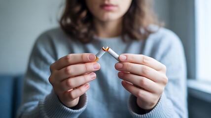 Obraz premium Womans hands breaking lit cigarette to quit smoking addiction