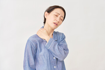 パジャマ姿の女性　肩こり　白背景